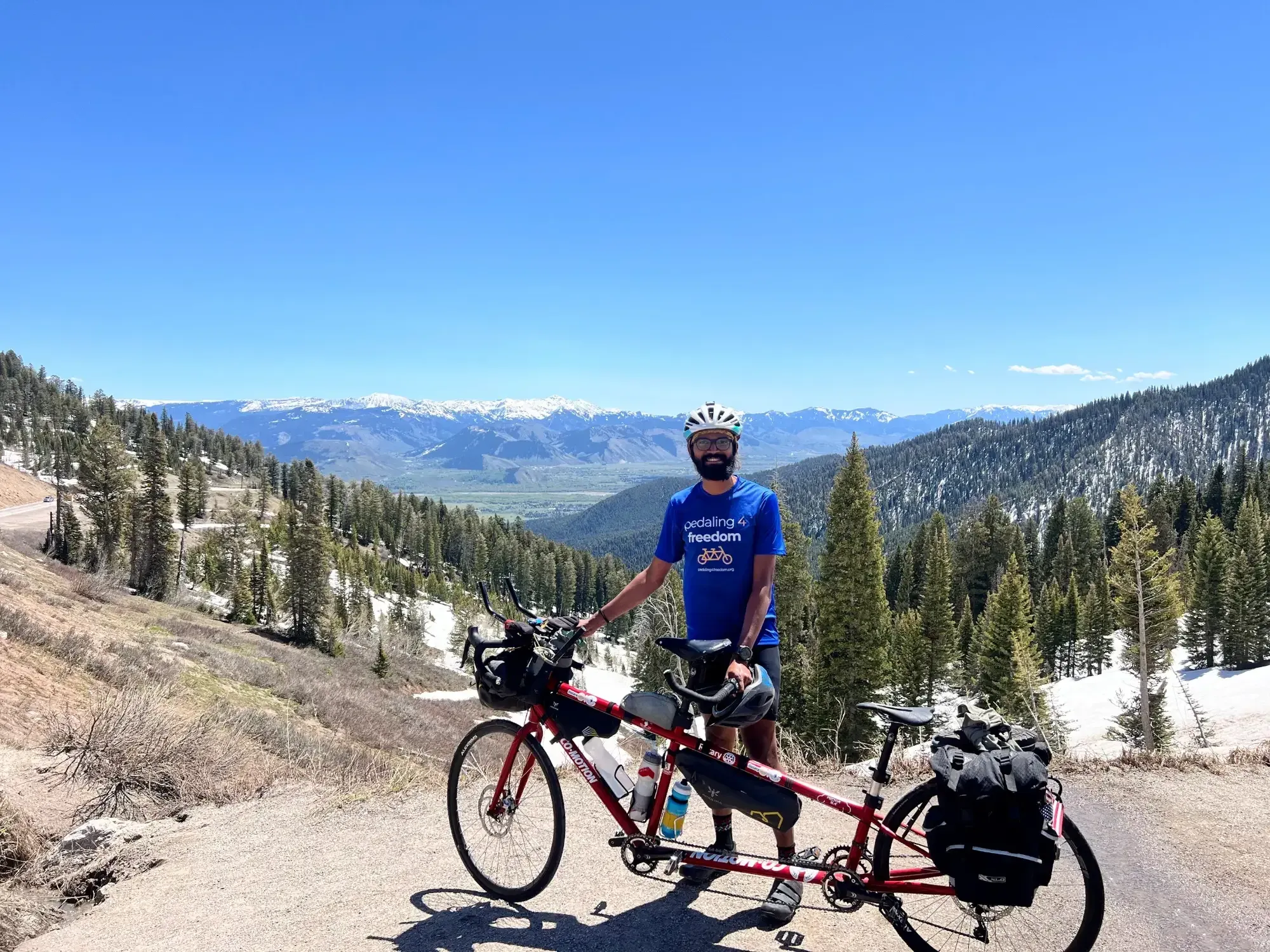 Naresh with the tandem on Teton Pass, snowy peaks behind