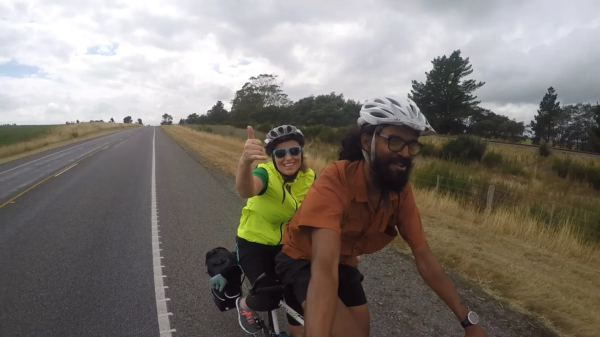 A rider in the back seat giving a thumbs up on an open country road