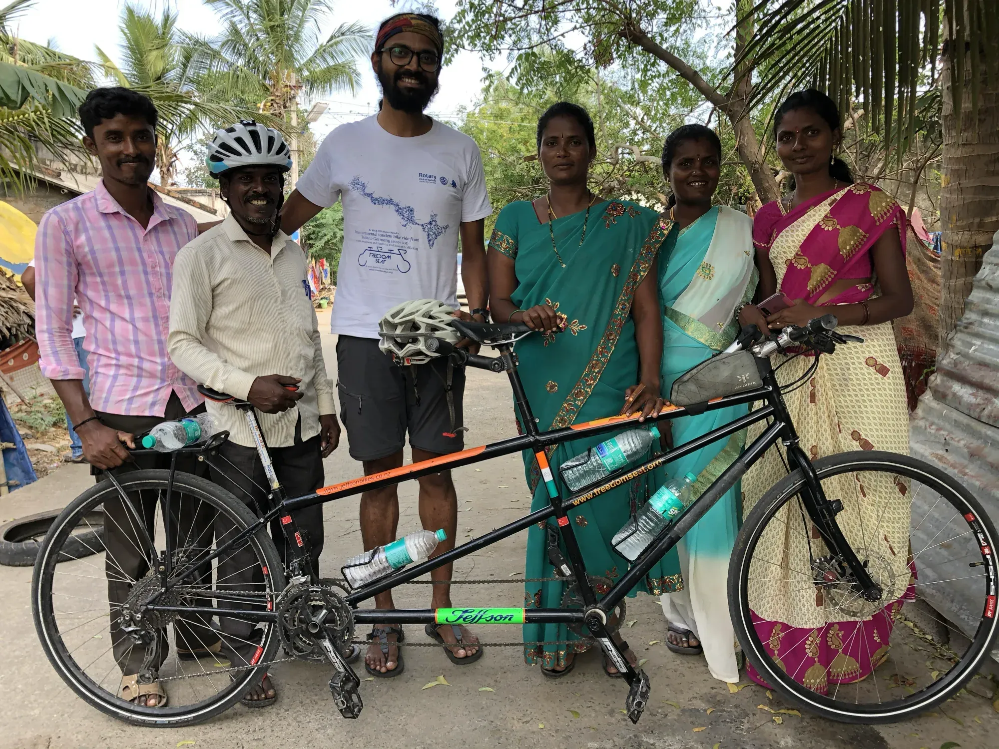 Naresh with a group of smiling men and women standing around the tandem