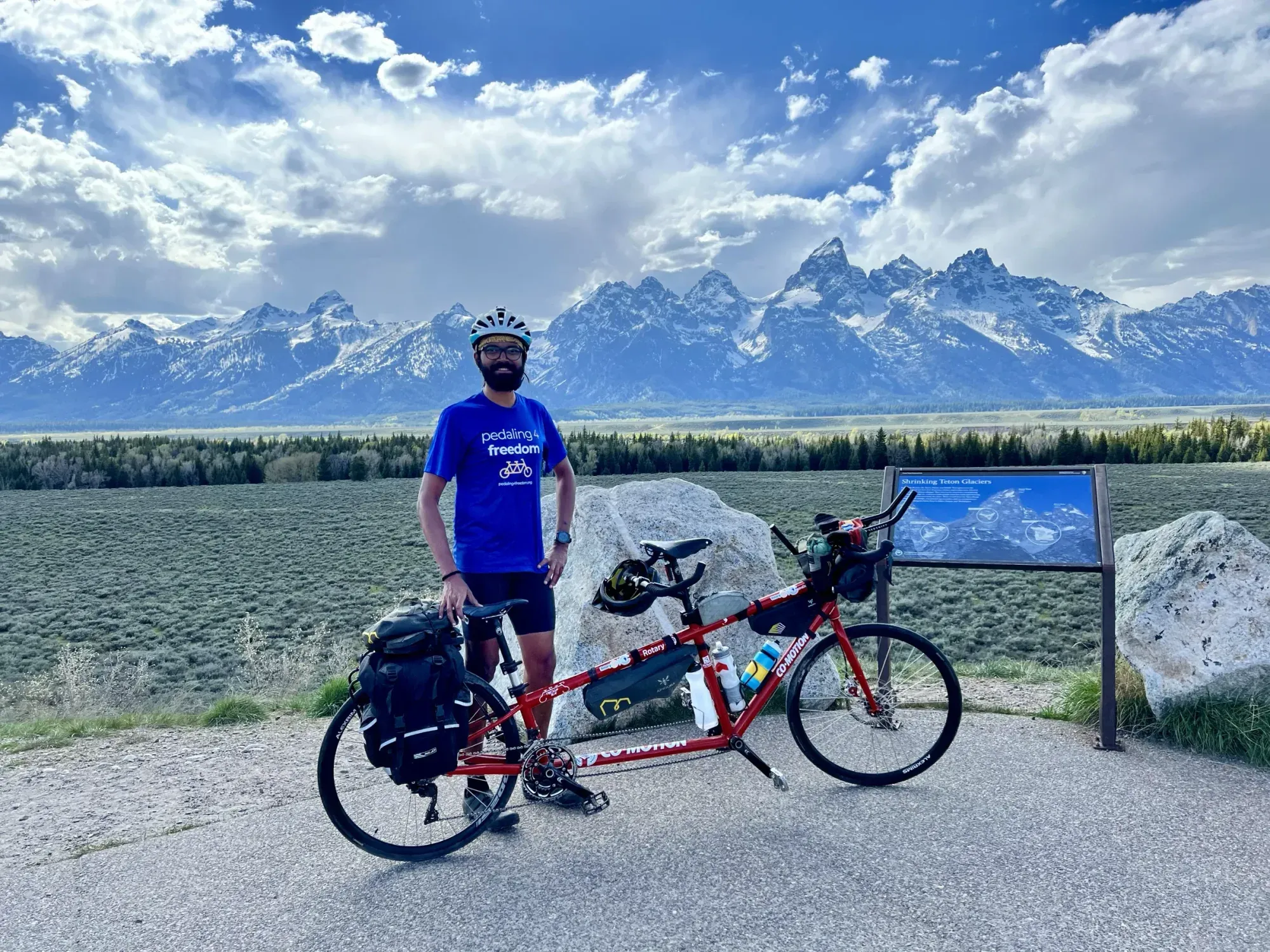 Naresh standing with his loaded tandem in front of the snow-capped Teton Range